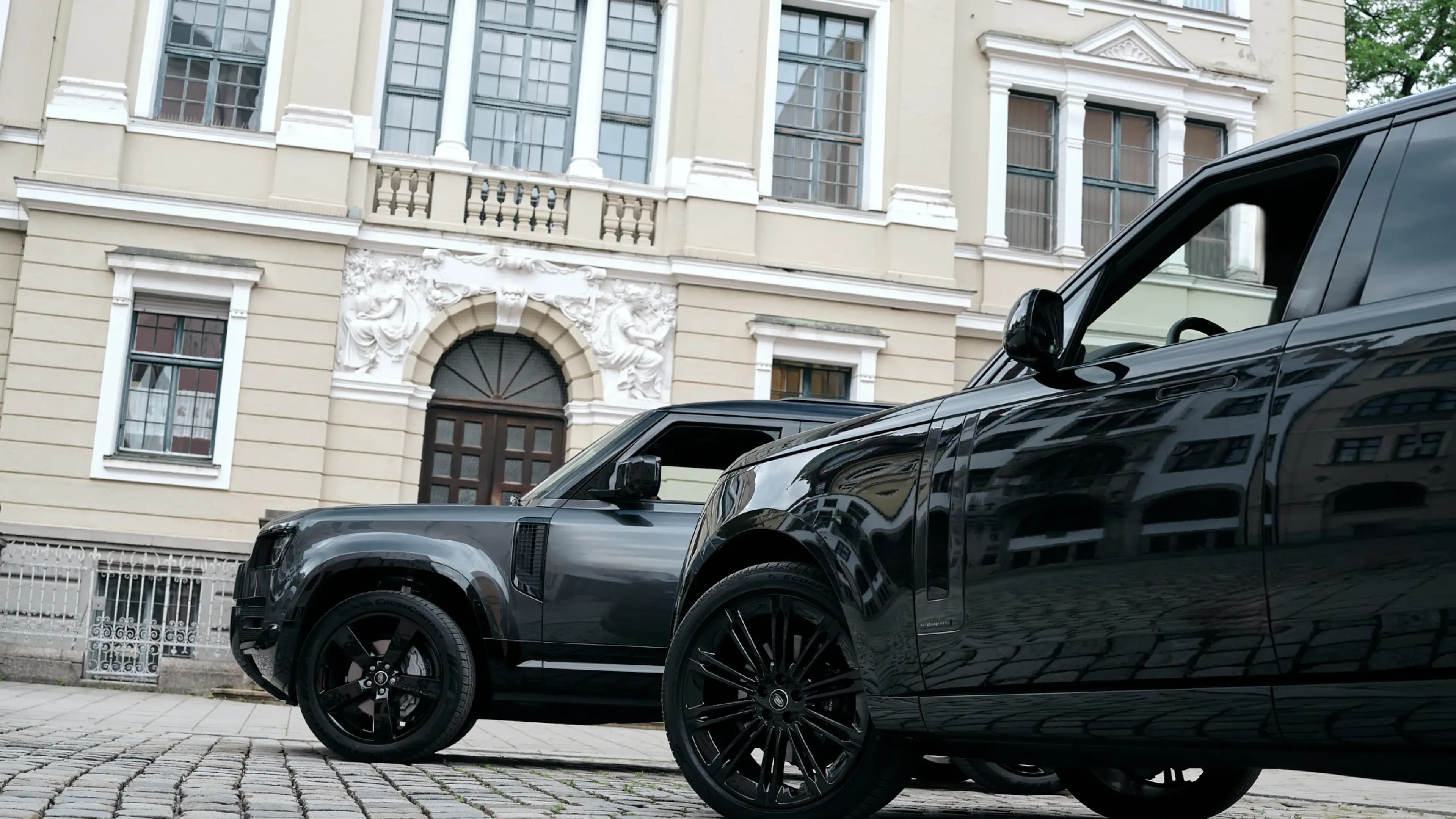Land Rover Defender and Range Rover Autobiography parked in front of a historic building in Munich.